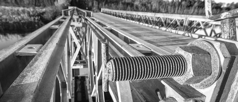 Fototapeta Keeping it together, abstract black & white close up of bolt with cap nut, fastening the top part of a steel gate to a bridge abutment.  Rod & cap nut fastening bridge parts together.