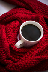 Obraz na płótnie Canvas White cup of hot coffee on the red scarf