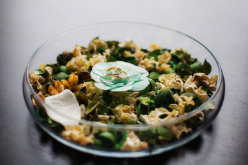 Wedding rings on decorative petals in bowl