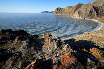 Rocky shore of lake Baikal in winter Rocky headland on the Western coast of lake Baikal sticks in ice-covered water body, forming a cozy Bay with a pebble beach 