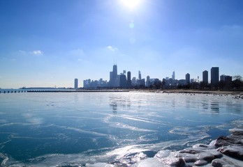Obraz premium Słońce świeci jasno nad panoramą Chicago, która odbija się na zamarzniętym jeziorze Michigan