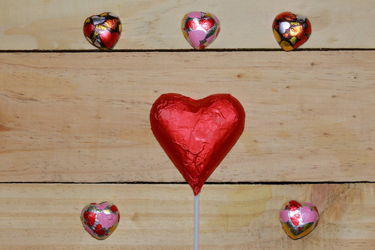 Chocolate heart wrapped in red  on wood. valentine concept. Spac