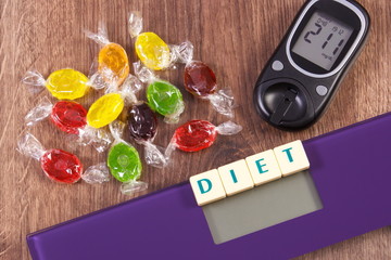 Electronic bathroom scale and glucometer with result of measurement and colorful candies, diabetes, slimming and reduction eating sweets