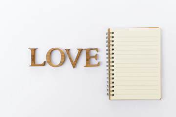 Wooden love and blank notebook on white background