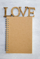 Wooden love and brown cover notebook on wood texture background