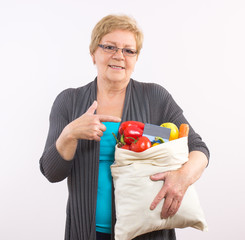 Senior woman showing shopping bag with credit card, paying for shopping