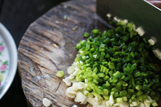 Handful of finely chopped green onions on striped wooden board