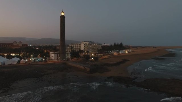 Aerial shot of Maspalomas Lighthouse with light in the dusk. Gran Canaria coast, Canary Islands