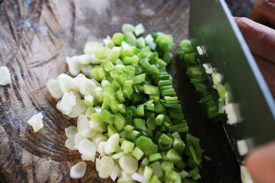 Handful of finely chopped green onions on striped wooden board
