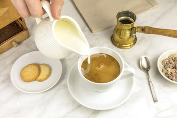 Milk poured into cup of coffee