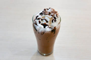 Chocolate frappe in a clear glass on a wood table, selective focus