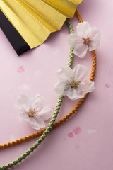 桜の花と金色の扇子と組紐のイメージ