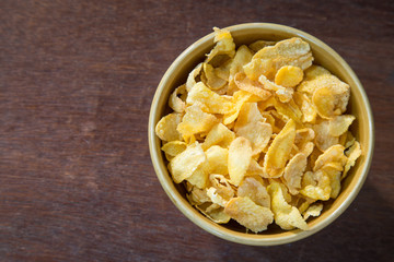 Bowl of corn flakes on wooden table.