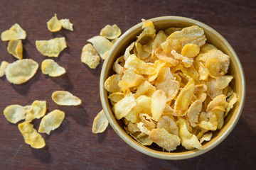 Bowl of corn flakes on wooden table.