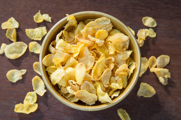 Bowl of corn flakes on wooden table.