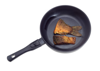 Fried slices of carp on frying pan on light background