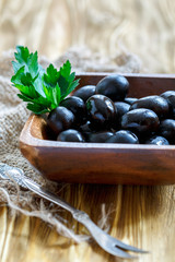 Wooden bowl with black olives.