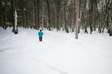 Fototapeta na wymiar elderly woman is engaged in Nordic walking outdoors in winter