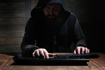 hacker in the black hood in a room with wooden walls