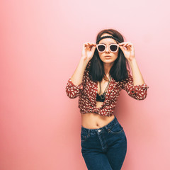 The woman is in the trend position and adjusts her pink glasses. Fashion clothing. Collection of spring. Vintage retro style.