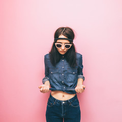 Woman in pink sunglasses, a blue shirt with polka dots and dark blue jeans. Minimal trend. Spring...