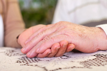 Elderly hands holding carer's hands