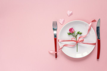 Festive table setting with cutlery, little rose and hearts on pi
