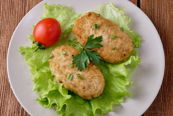Chicken cutlets with vegetables on a wooden background