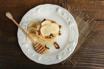 Pancakes with bananas, nuts in the plate and spoon. Top view.