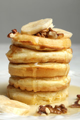 Stack of pancakes with bananas and nuts in the plate.