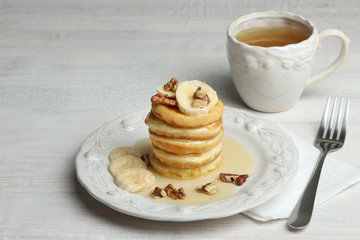 Pancakes with bananas ,nuts to a plate and cup of tea.