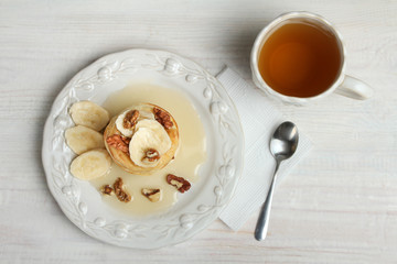 Pancakes with bananas ,nuts to a plate and cup of tea. Top view.