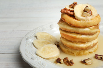 Stack of pancakes with bananas and nuts in the plate.
