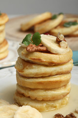 Stack of pancakes with bananas and nuts in the plate.
