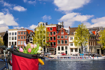 Famous Amsterdam with basket of colorful tulips against canal in Holland
