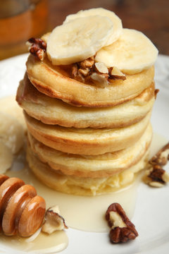 Stack of pancakes with bananas and nuts in the plate.