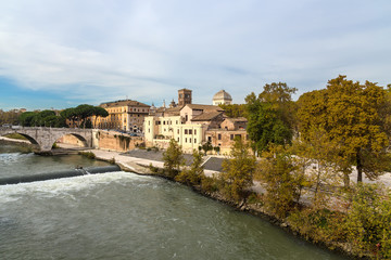 Fototapeta na wymiar Rome. Italy. View from the right bank of the Tiber: the Pons Cestius (44 BC), the Basilica of St. Bartholomew (998) on the Tiberina island