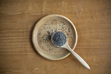 Top View of Chia Seeds with Wooden Plate and Spoon on Wood Table