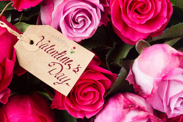 bunch of blooming fresh dark and light pink roses with empty tag close up with happy valentines day greetings