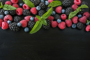 Various fresh summer berries on black background. Ripe blueberry, raspberry and blackberry with...