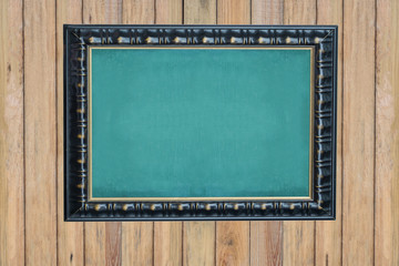 Empty green chalkboard with black wooden frame  on vintage wall