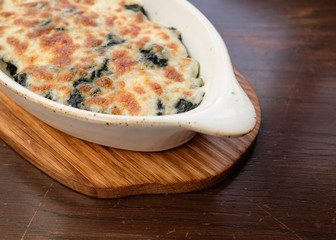 baked spinach in white bowl serve with tray wooden.