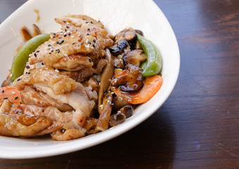 side view of rice and yellow curry chicken with vegetable serve in white bowl on wooden table