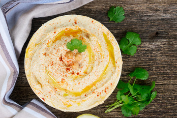 Plate of hummus on wooden table, top view