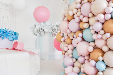 Boxes with flowers and a large pudrinitsa with balls and balloons in room decorated for birthday party.