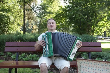 Man with accordion or harmonica in summer park