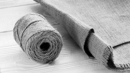 hank jute yarn with sackcloth on white textured  wooden table, black and white
