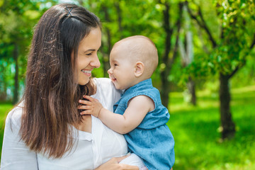 Mother holds her daughter in her arms, in the park. Close-up. The concept of family values.