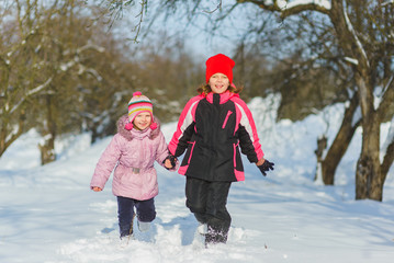 joyful children playing in snow. Two happy girls having fun outside winter day