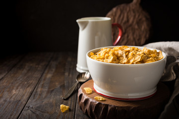 Corn flakes with milk on dark wooden background. Copy space. Helthy breakfast concept.